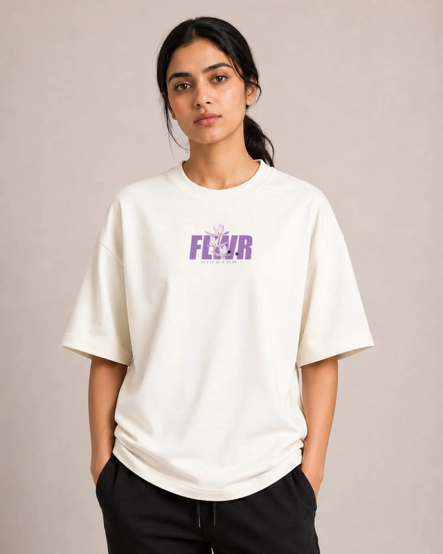 Person wearing a off-white t-shirt with 'Fleur' printed in purple on a plain background