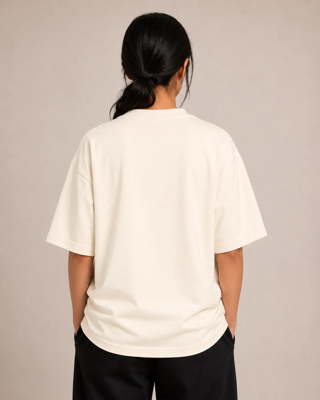 Person wearing a off-white t-shirt and black pants against a beige background