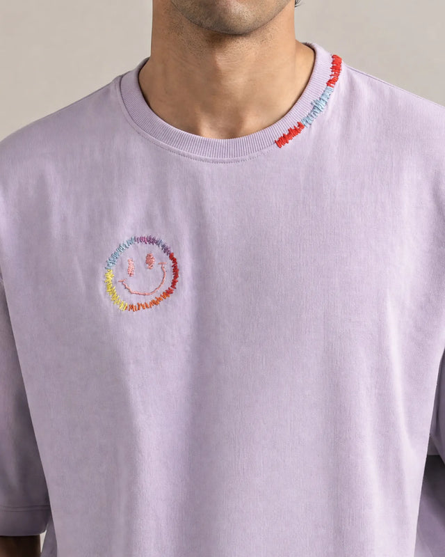 Light lavender t-shirt with a colorful smiley face design on a neutral background