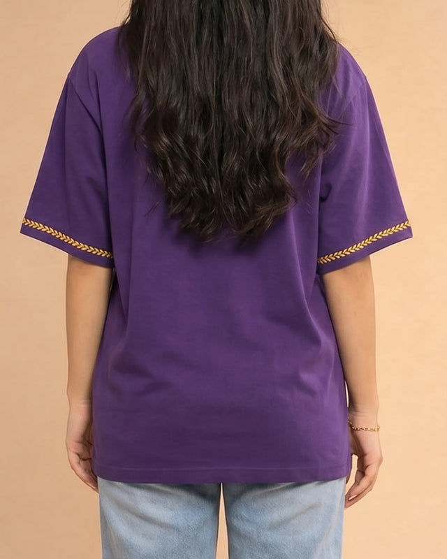 Purple top with gold trim worn by a person on a beige background