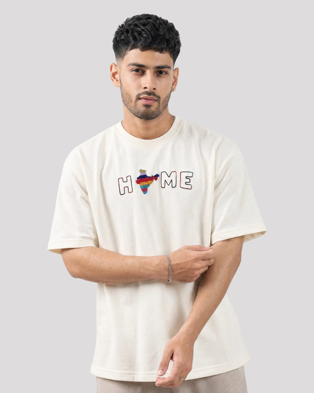 Man wearing a white t-shirt with colorful design and text on a plain background