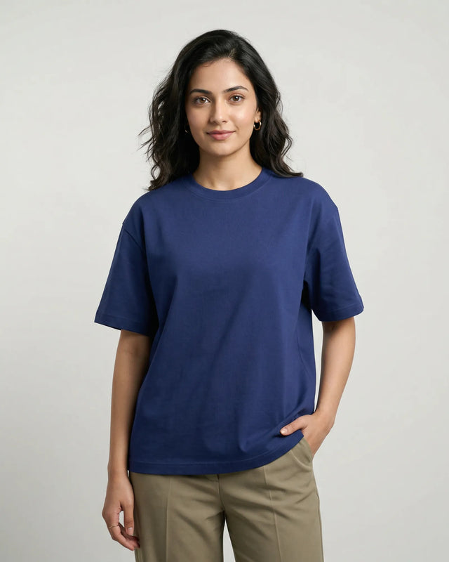Woman wearing a royal blue t-shirt and beige pants on a plain background