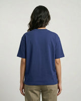 Person wearing a royal blue t-shirt and beige pants on a plain background