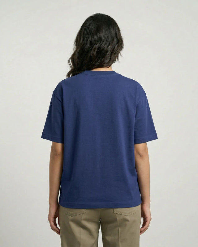 Person wearing a royal blue t-shirt and beige pants on a plain background