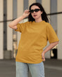 Woman wearing a mustard yellow t-shirt and sunglasses outdoors.