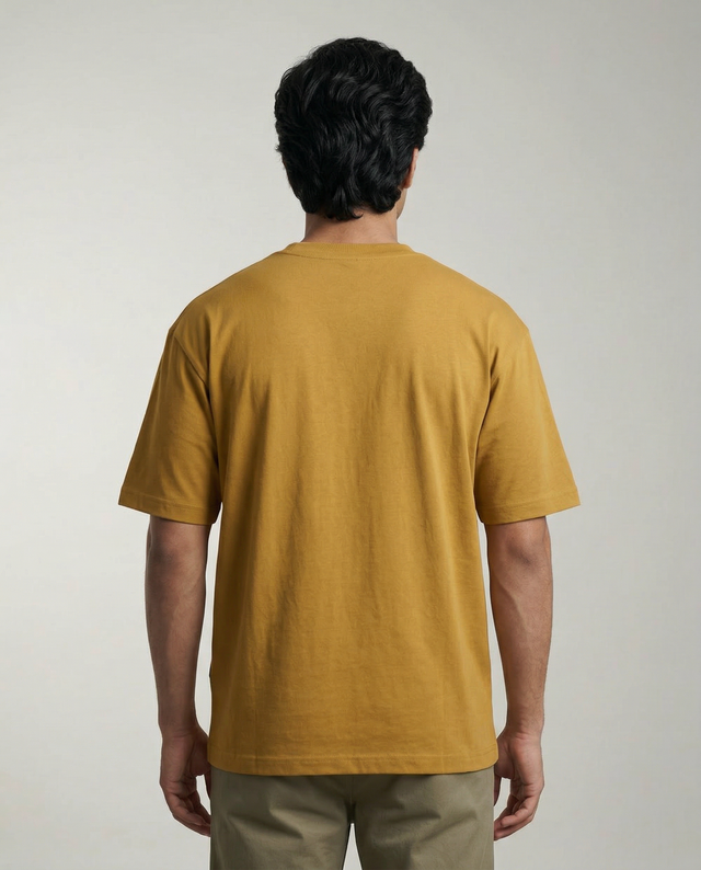 Person wearing a mustard yellow t-shirt against a plain background
