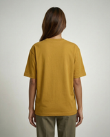 Person wearing a mustard yellow t-shirt on a plain background
