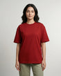 Woman wearing a red t-shirt and green pants on a plain background
