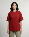 Woman wearing a red t-shirt and green pants on a plain background
