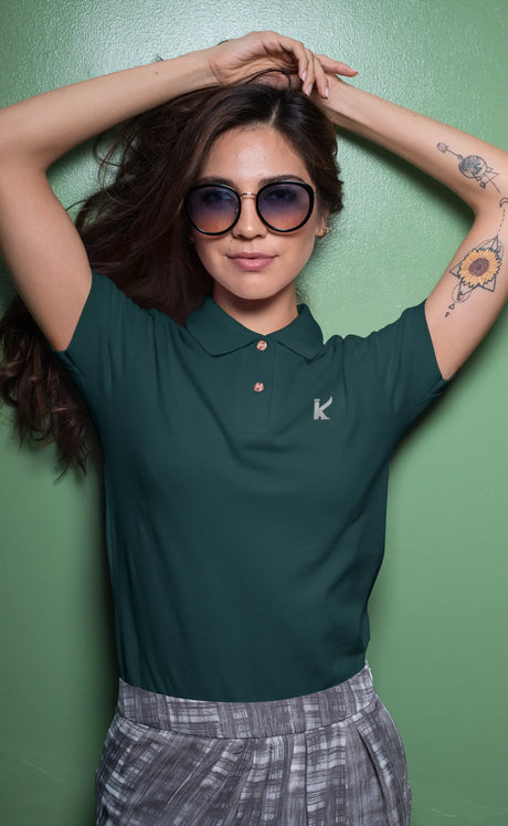 Woman wearing a petrol blue polo shirt with a logo against a green background