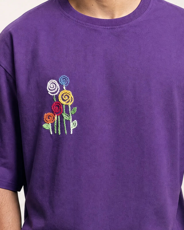 Purple t-shirt with embroidered flowers on a plain background