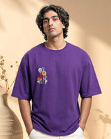 Man wearing a purple t-shirt with floral design against a beige background