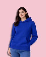 Woman wearing a royal blue hoodie against a pink background