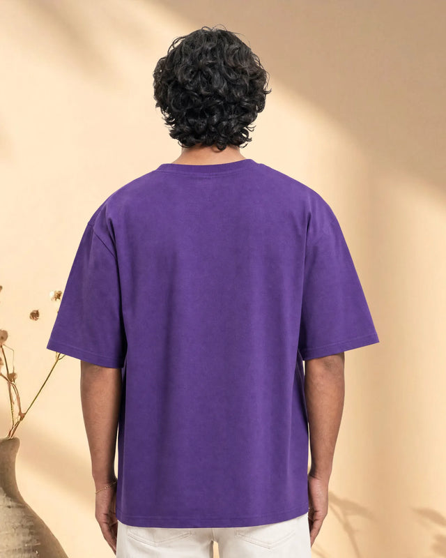 Person wearing a purple t-shirt against a beige background