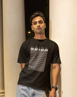 Man wearing a black t-shirt with text standing against a neutral background