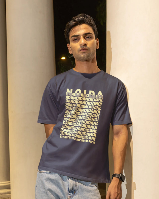 Man wearing a dark blue t-shirt with text design, standing indoors.