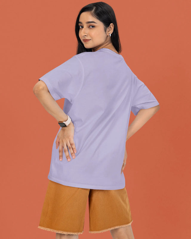 Woman wearing a light purple t-shirt and brown shorts against an orange background
