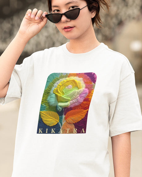 Woman wearing a white t-shirt with a colorful rose graphic and 'Kikatra' branding.