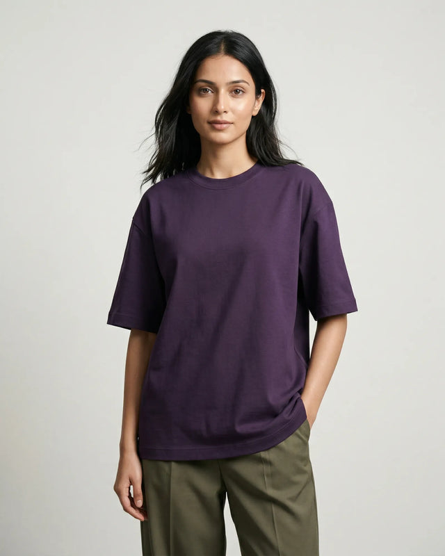 Woman wearing a purple t-shirt and green pants on a plain background