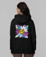 Woman wearing a black hoodie with a colorful flower design on the back against a gray background
