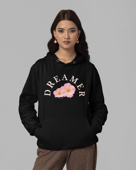 Woman wearing a black hoodie with 'DREAMER' and floral design on a gray background