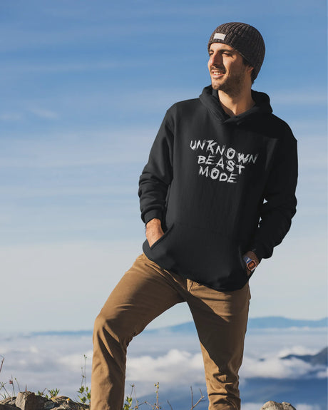 Man wearing a black hoodie with text standing outdoors against a blue sky.