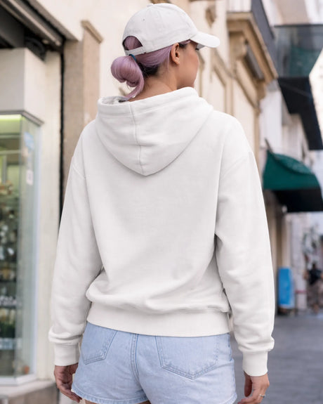 Person wearing a white hoodie and light blue shorts walking on a street.