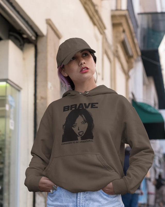 Woman wearing a brown hoodie with a graphic design and text, standing on a street.
