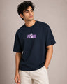 Man wearing a navy blue t-shirt with a logo and text on a beige background