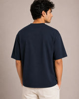 Man wearing a navy blue t-shirt against a beige background