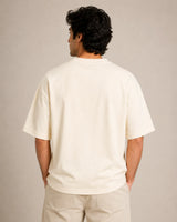 Man wearing a plain off-white t-shirt against a neutral background