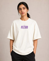 Person wearing a off-white t-shirt with 'Fleur' printed in purple on a plain background