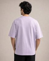 Person wearing a light lavender  t-shirt against a beige background