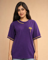 Woman wearing a purple t-shirt with yellow flower embroidery on a beige background