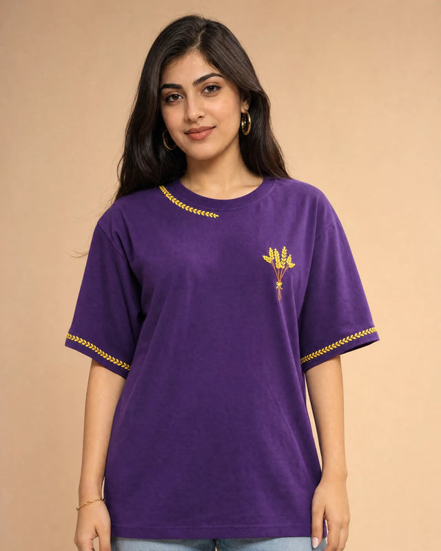 Woman wearing a purple t-shirt with yellow flower embroidery on a beige background