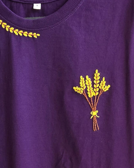Purple t-shirt with yellow embroidered design of a bouquet on a plain background