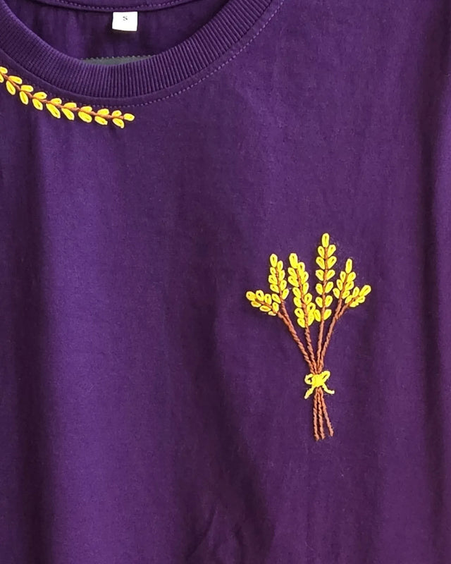 Purple t-shirt with yellow embroidered design of a bouquet on a plain background