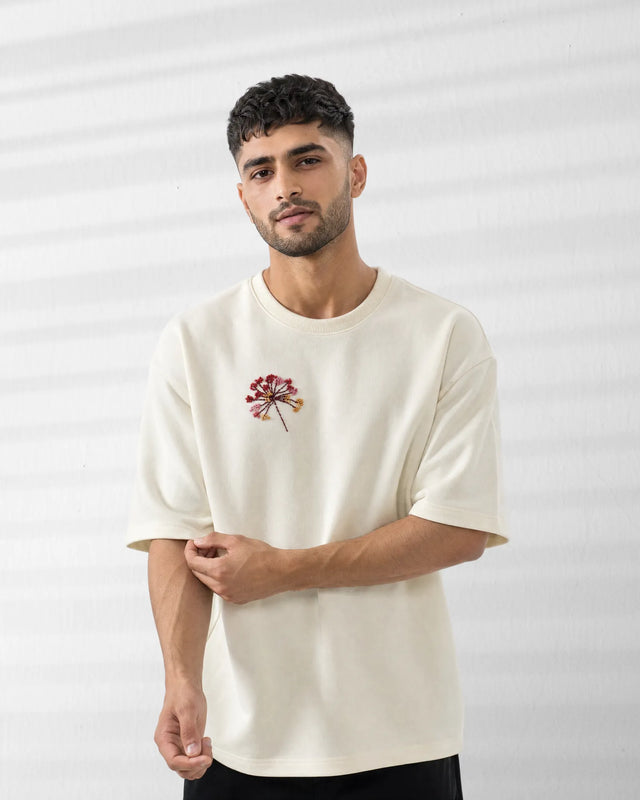 Man wearing a Off-White t-shirt with a small floral design on a plain background