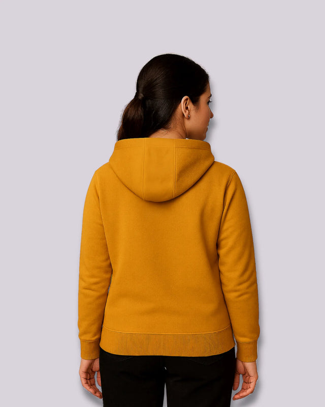 Woman wearing a mustard yellow hoodie on a light gray background