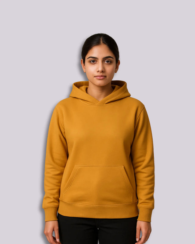 Woman wearing a mustard yellow hoodie on a light gray background