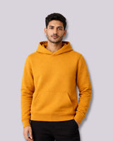 Man wearing a mustard yellow hoodie against a light gray background
