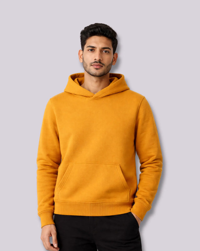 Man wearing a mustard yellow hoodie against a light gray background