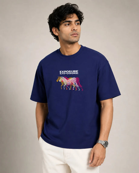 Man wearing a royal blue t-shirt with a colorful graphic and text on a plain background