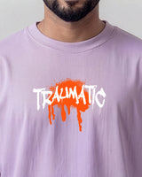 Person wearing a light lavender t-shirt with 'TRAUMATIC' graphic design.