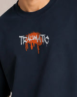 Navy blue sweatshirt with 'TRAUMATIC' text and orange splashes on a neutral background