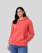 Woman wearing a coral hoodie on a gray background