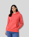 Woman wearing a coral hoodie on a gray background