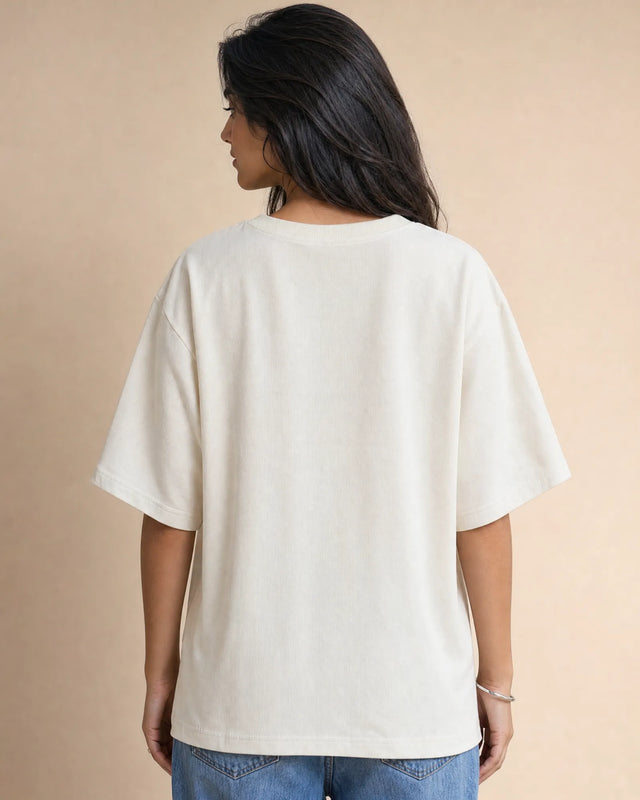 Person wearing a plain white t-shirt and blue jeans on a beige background