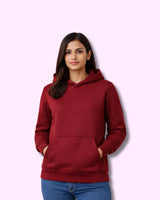 Woman wearing a maroon hoodie against a pink background