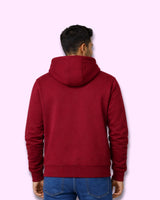 Man wearing a maroon hoodie on a light pink background